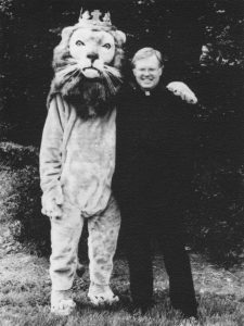 Father Charles David Sherrer standing next to a person in a lion costume.