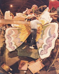People decorating butterfly wings on a parade float.