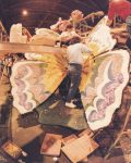 People decorating butterfly wings on a parade float.