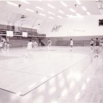 Players playing basketball on an indoor gymnasium basketball court.