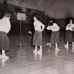 Cheerleaders on a gymnasium floor.