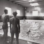 Instructor and students in an indoor swimming pool.