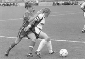 Michelle French goes after the soccer ball with an opponent behind her.