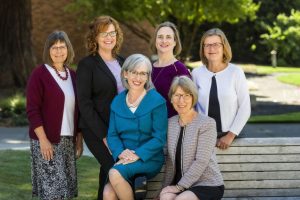 School of Nursing Administrators pose near at a bench outdoors.
