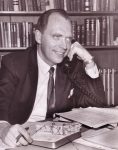 Doctor Arthur Schulte with the telephone at his left ear and right hand positioned at his desk calendar.