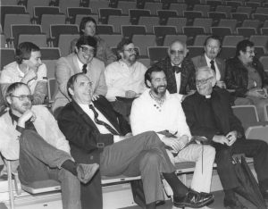 Doctor Arthur Schulte sitting with faculty and staff members in the Chiles Center seats.