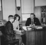 Doctor Arthur Schulte and two students sitting at a desk in his office.