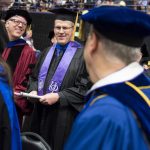 Faculty members dressed in academic regalia at a University commencement ceremony.