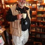 Doctor Mark Eifler holding a beverage mug and wearing a camera around his neck.