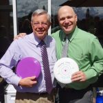 Doctor Robin Anderson and Doctor John Watzke holding frisbees and smiling.