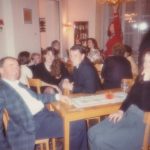 People seated around several tables and talking to each other.