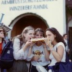 Three girls biting into a large piece of bread.