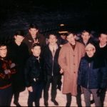 Group of eleven people singing in the snow.