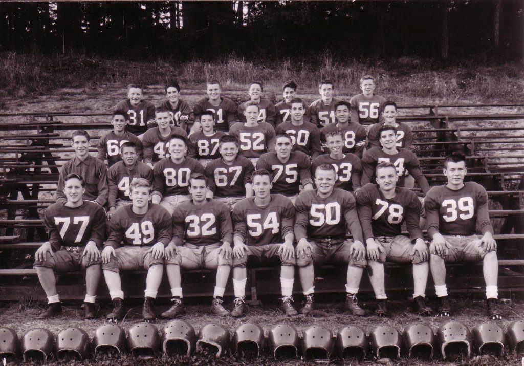 Football team in uniform sitting on benches.