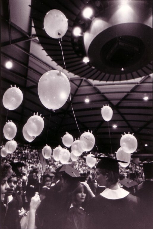 Nursing graduates release surgical glove balloons into the air.