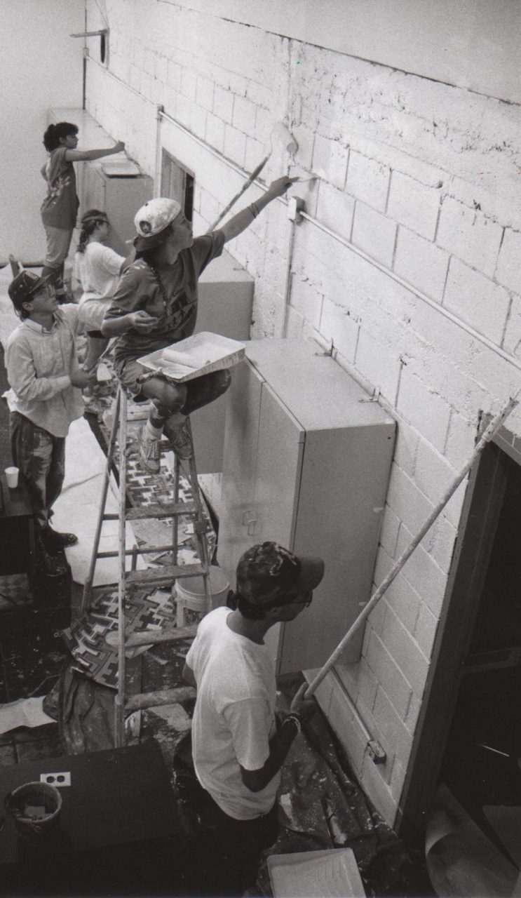 Volunteers painting the side of a building.