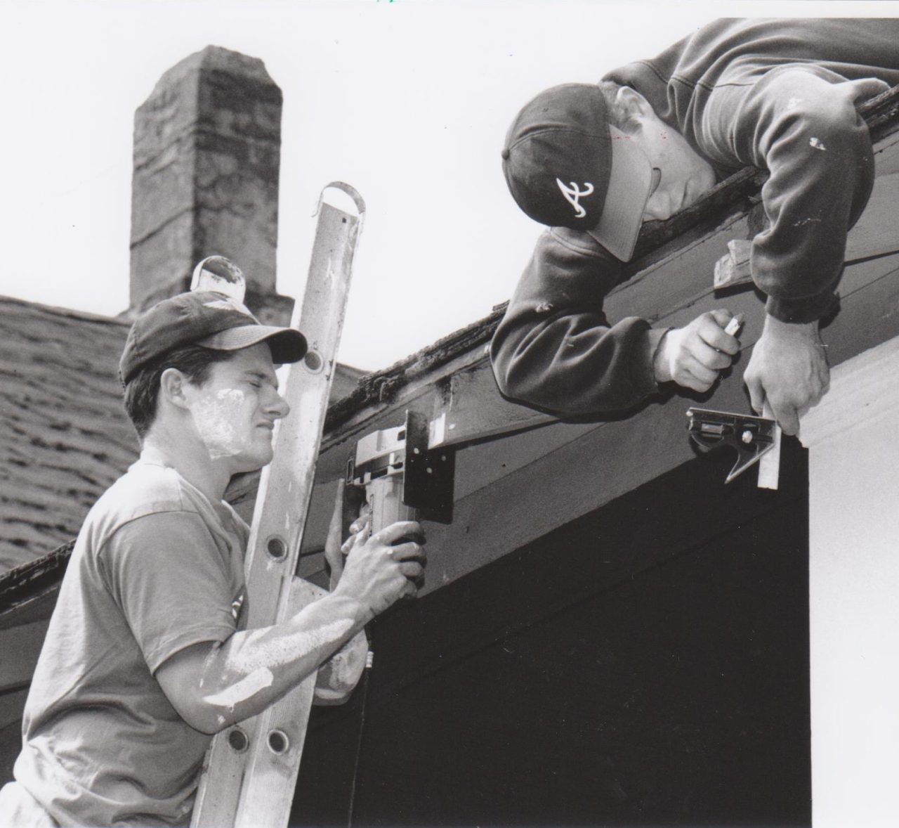 Student volunteers sanding a roof beam.