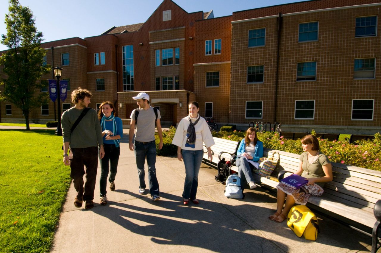 Students walking and sitting in front of Corrado Hall.