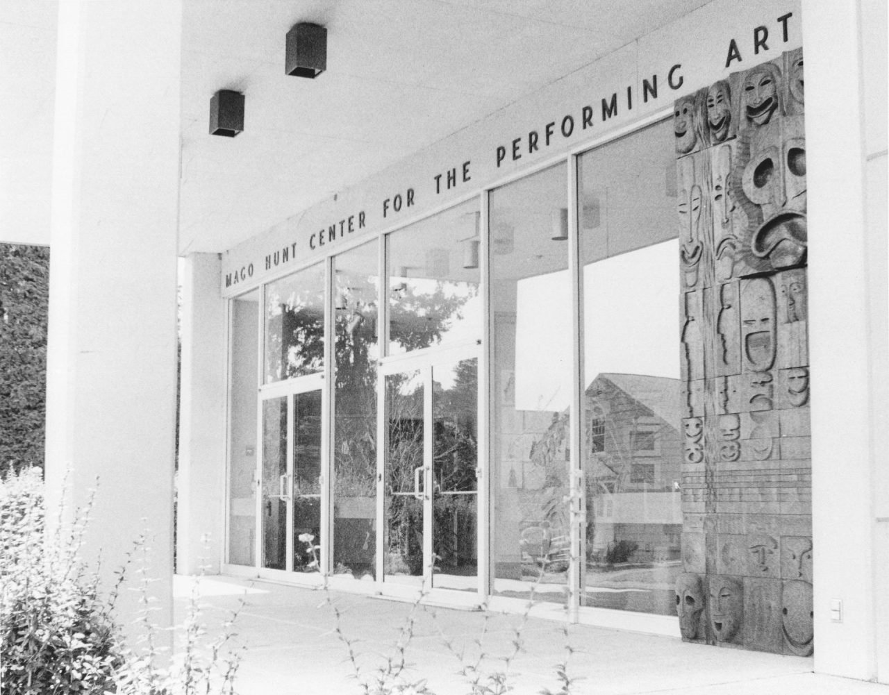 Front doors of Mago Hunt Center for the Performing Arts with carved wooden drama masks on the side panel.