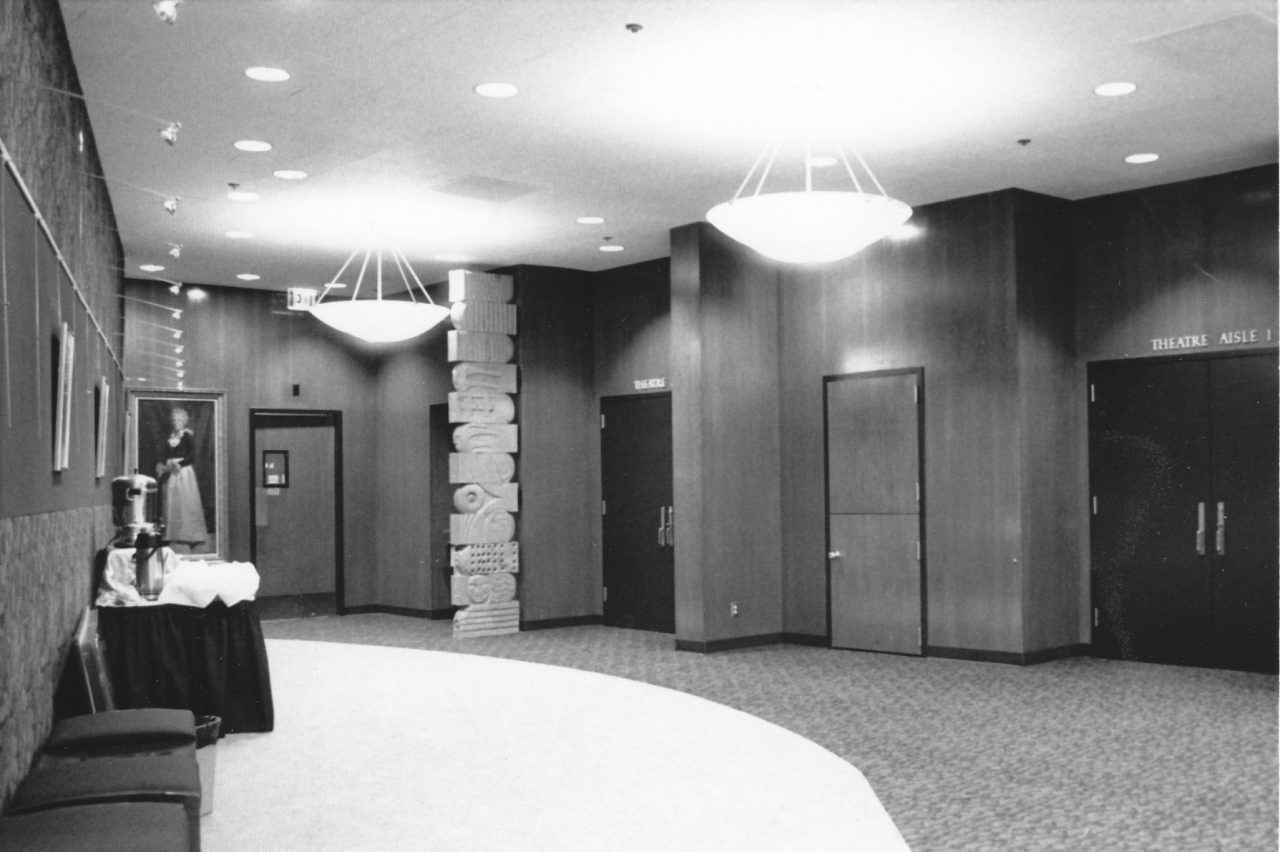 Lobby of a building with chairs, table, entry doors.