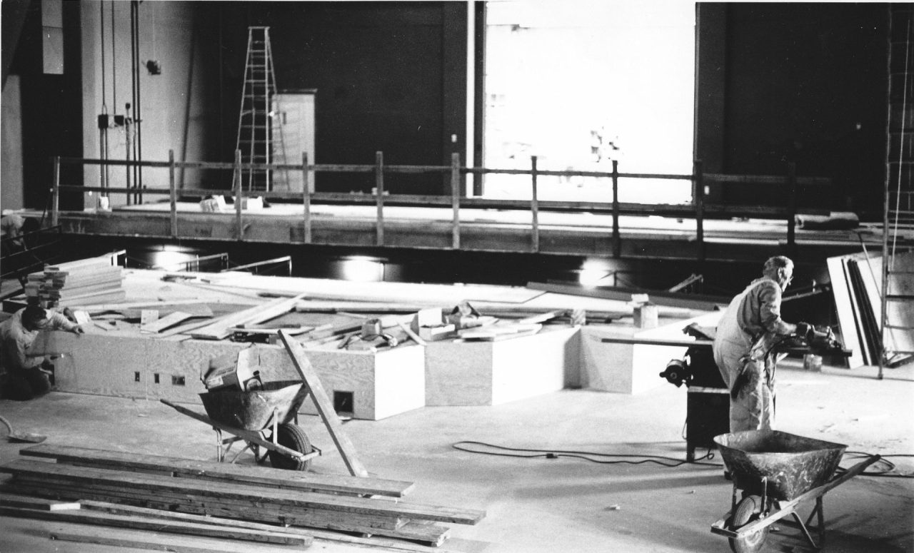 Construction workers working on a partially constructed stage.
