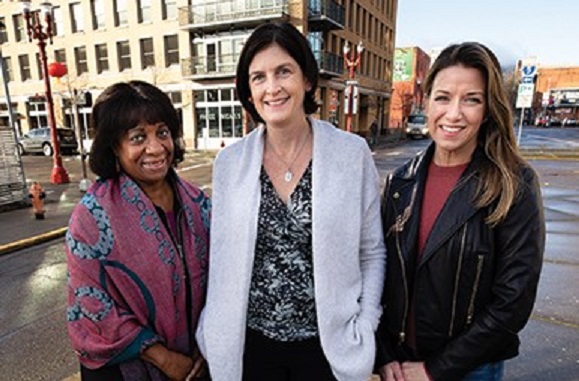 Three women standing on street in downtown Portland.