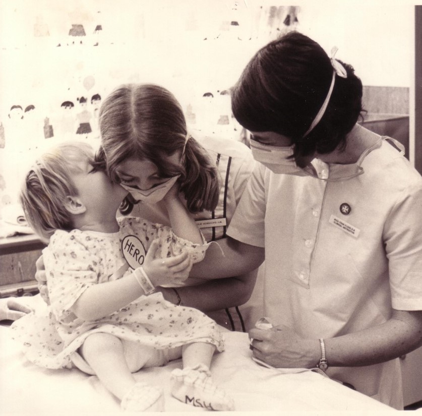 Supervising nurse and student nurse tending to baby on a hospital bed.