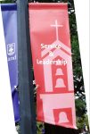 Red vinyl banner with an image of the bell tower with overlay of the words, Service & Leadership.