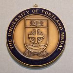 Round purple and gold medal with the words University of Portland Medal and University seal in the center