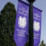 Pair of University of Portland Teaching Faith Service Banners hanging from a light pole.
