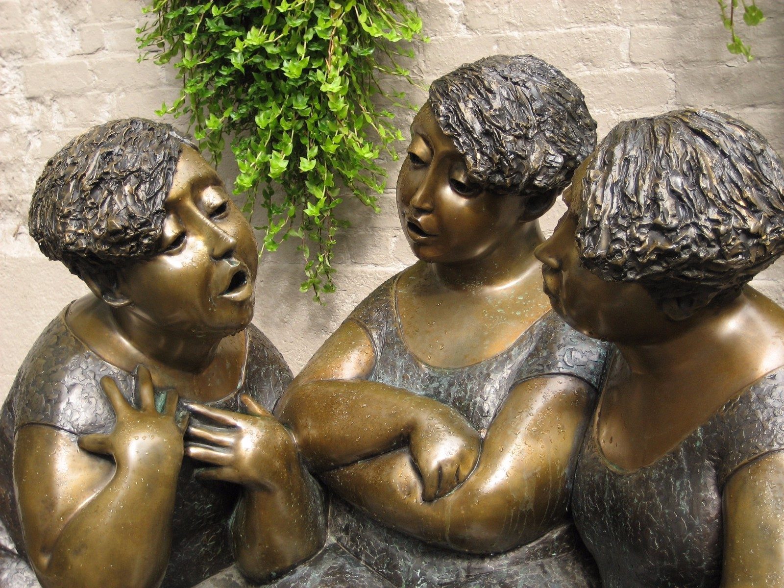 three bronze statues of women. they are in conversation