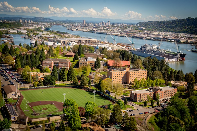 an aerial view of campus, with buidlings in the foreground and the williamette river in the background