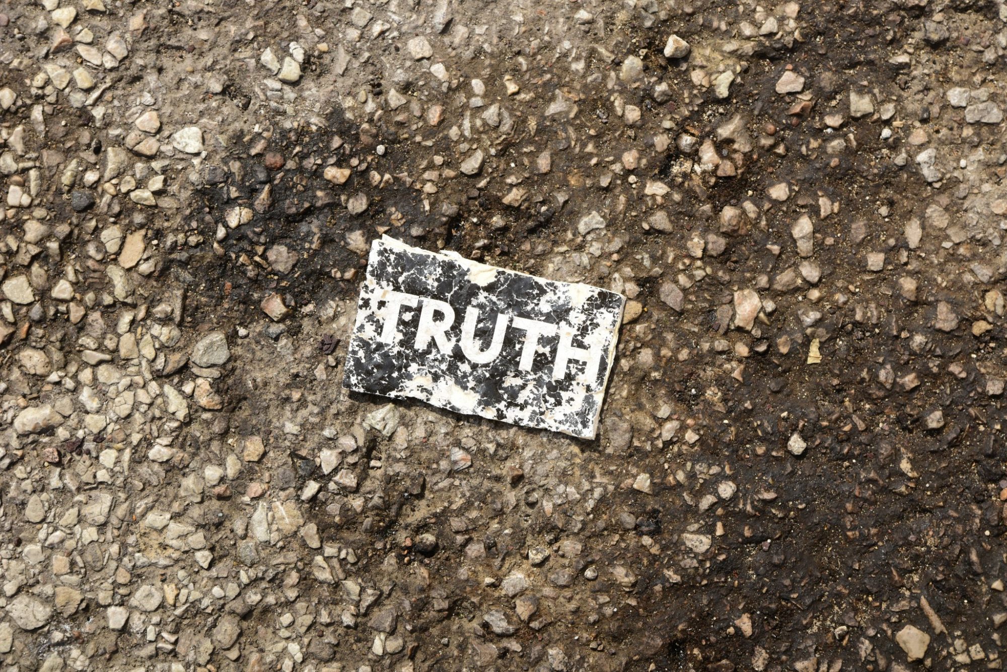 Small sign saying truth on pavement